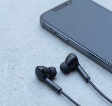 A close-up shot of a modern smartphone and wireless earbuds resting on a light blue concrete surface, representing mobility and modern tech consulting. Minimalist composition, clean lighting, North American tech style, professional and sophisticated, high detail.