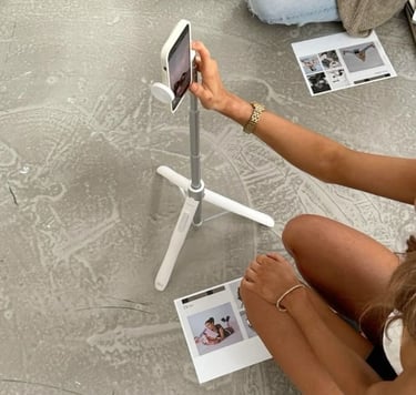 Woman filming content with a phone on a tripod and printed materials on the floor.
