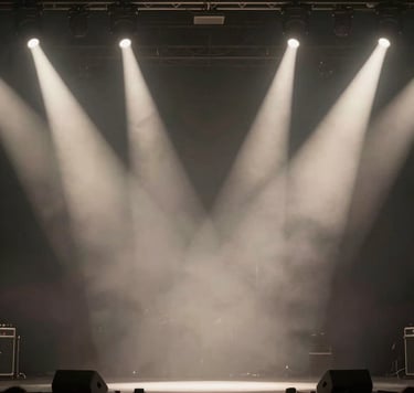 Artistic photography of a blurred Dutch concert stage seen from the wings, with bright off-white spotlights cutting through a hazy dark gray atmosphere. The composition is minimalist and elegant, focusing on the raw energy of a live music setting.