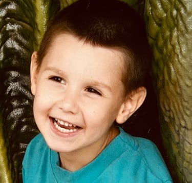 A giggling 6-year-old boy with brown eyes.