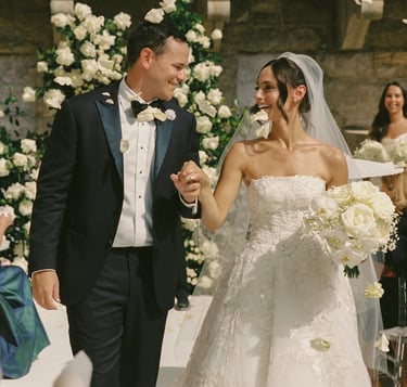 Happy just married couple walking down the aisle full of white flowers
