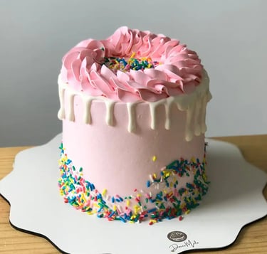 Bolo decorado com glacê rosa e confeitos coloridos, perfeito para festas e celebrações. Uma delícia