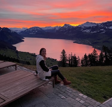 a woman sitting on a bench in front of a sunset
