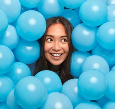 a woman in a ball pit with blue balloons