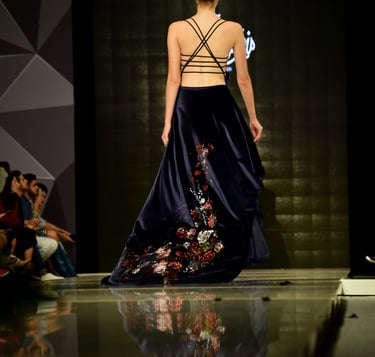 A woman fashion model on the runway in a long dress with a sexy back.
