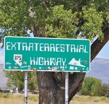 a green street sign with a road sign that says extra terrestrial highway