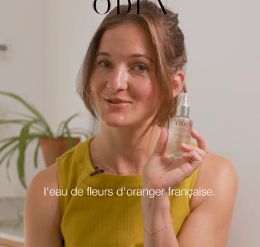 a woman in a yellow dress holding a bottle of cosmetic