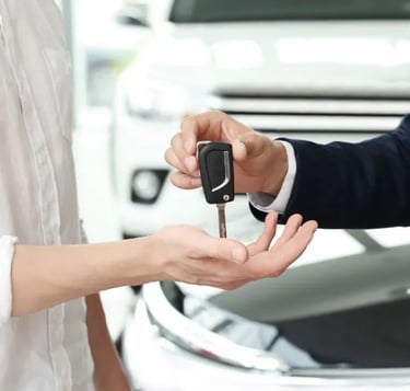Remise de clés entre deux personnes devant une voiture blanche, symbolisant la vente ou la livraison