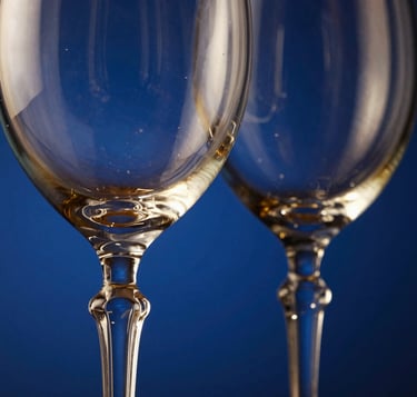 Close-up of elegant hand-blown crystal wine glass rims catching hard dramatic side-lighting, deep blue background, 35mm