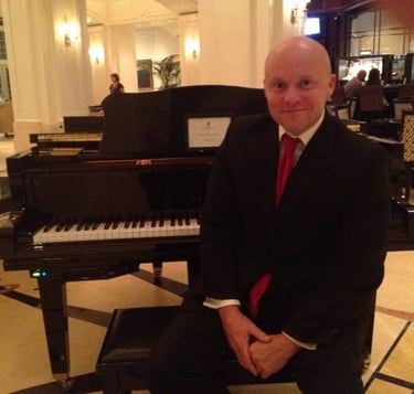Mark Bulmer Performing On Piano In A Suit