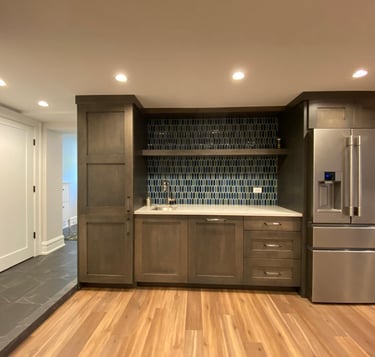 Basement wet bar with natural stone countertop, tile backsplash, and built-in storage cabinets