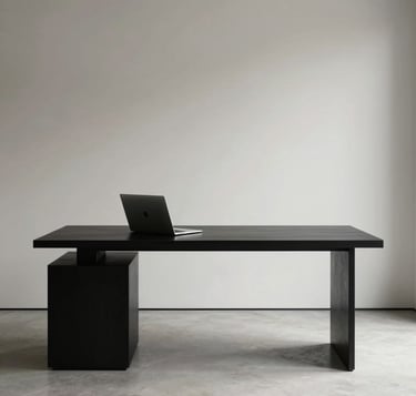 A high-end, minimalist North American design studio interior with a single matte black desk and a high-performance silver laptop. The lighting is soft and directional, creating a sophisticated and professional atmosphere with a palette of rich black and off-white.