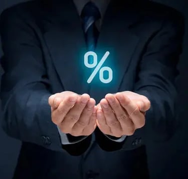 En affärsman i mörk kostym håller fram sina händer med en lysande procentsymbol.