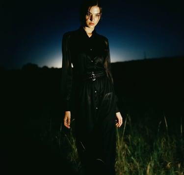 a woman in a black dress standing in a field