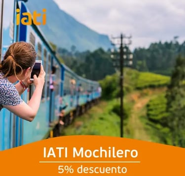 A backpacker taking a photo from a blue train traveling through lush green mountains in Sri Lanka.