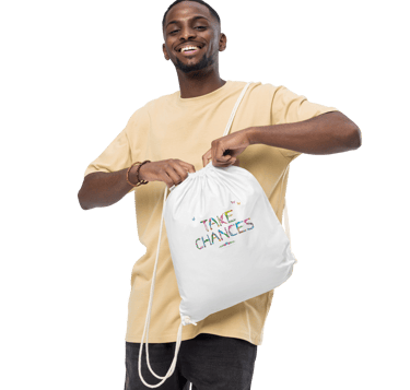 A man holding a tote bag with the words Take Chances printed on in tropical exotic wordart