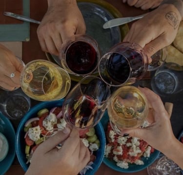 a group of people holding glasses of greek wine and toasting