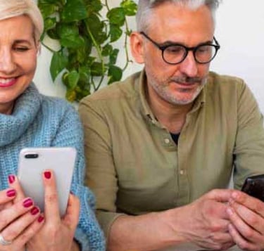 hombre y mujer sonriendo mirando su móvil