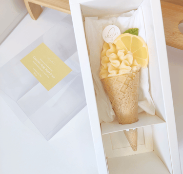 An ice cream-shaped soap inside a white box with lemon slice and mint leaf made of soap