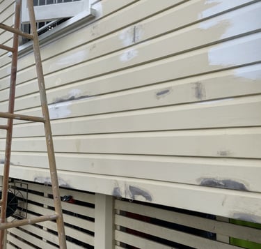 Exterior wall preparation in Zillmere showing patched weatherboards before repainting