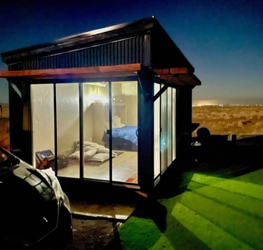 a small cabin with a bed and a car parked in front of it