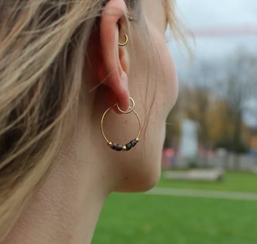 Frau trägt goldene Creolen mit Kokosperlen