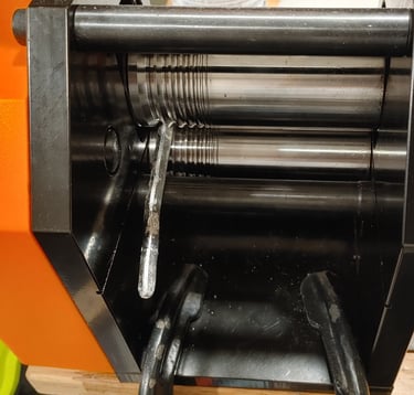 Silver sheet being flattened through a rolling mill.