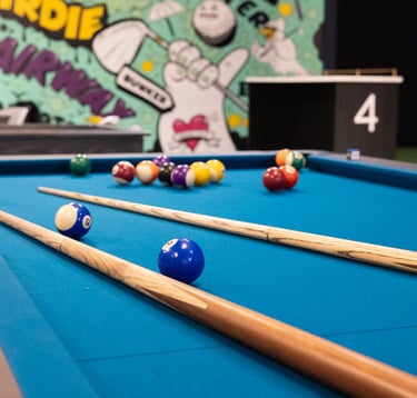 A pool table in a premium indoor golf simulator bay, 1IRON indoor golf