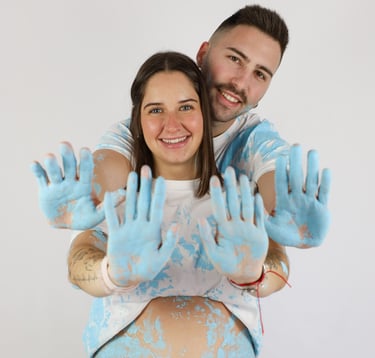 Sessió de fotos de gender reveal a Girona d'una parella amb pintura blava en estudi fotogràfic