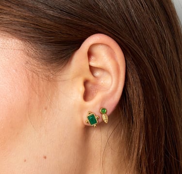 a woman wearing a pair of emerald earrings and a pair of emerald earrings