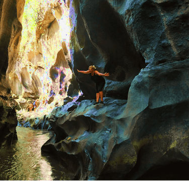 a person standing in a cave in a canyon