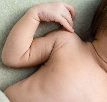 Detall de mans i cos d'un bebè nounat en una sessió de fotos newborn a Girona en estudi fotogràfic