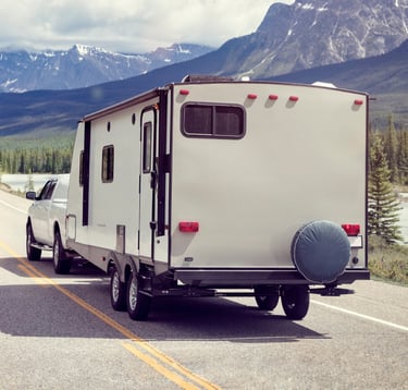 RV driving down road with mountains and trees.