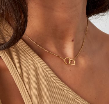 a woman wearing a gold necklace and a gold necklace