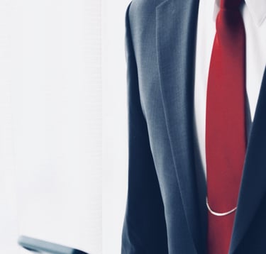 Um homem de paletó e gravata segurando um celular nas mãos