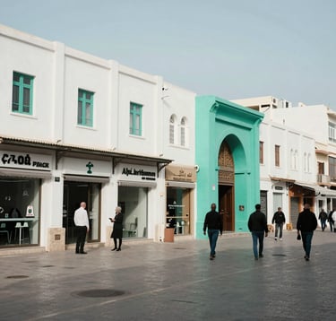 A street-level shot of a busy commercial district in Algiers, showing modern storefronts and people engaged in professional daily life. The composition is balanced and clean, using a natural light palette of white and sea green, reflecting North African and European urban style.