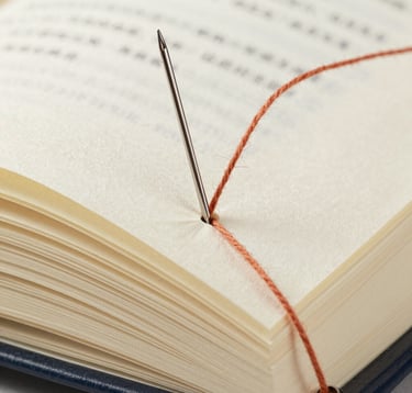 Macro photography detail showing a needle and terracotta thread piercing a thick, creamy book page. The focus is sharp on the texture of the paper and the tension of the thread. Clean, high-end editorial style.
