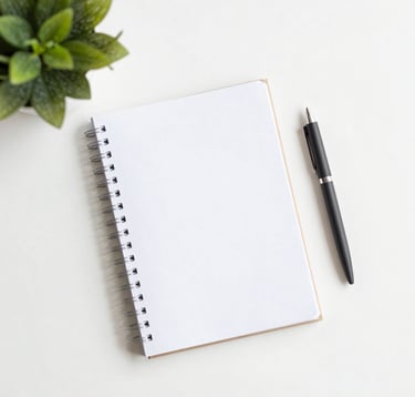 A clean, modern flat-lay photography composition featuring a physical journal, a pen, and a small green plant. Bright, airy lighting with plenty of white space. No digital technology in the frame. Peaceful and inviting tone with soft natural colors.