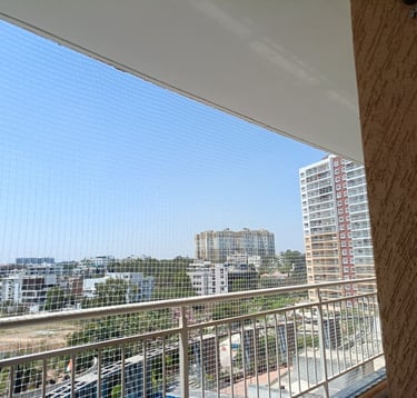 a balcony with a view of balcony safety nets ,a city skyline in bengaluru