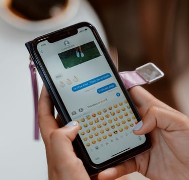 Una persona que utiliza un iPhone para enviar mensajes de texto y emojis mientras está sentada en un