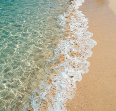 Close-up shot of crystal clear turquoise waves gently washing over golden sand in Puerto Escondido. High-end photography with soft lighting and a focus on the natural beauty of a Mexican coastal paradise.
