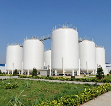 A professional shot of a modern environmental engineering facility in Vietnam. Clean, industrial design with white tanks and green landscaping. Clear blue sky, bright daylight, emphasizing cleanliness and sustainable technology.