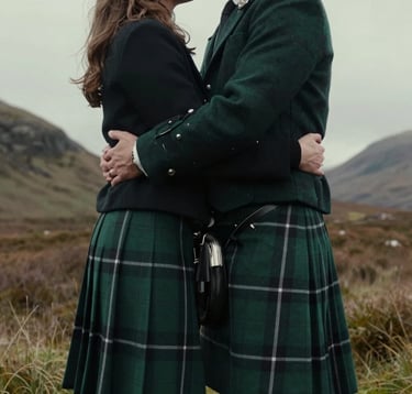 A cinematic close-up of a couple embracing in a glen in the Scottish Highlands. The groom is wearing a traditional forest green tartan kilt. The lighting is soft and moody, emphasizing the romantic and Northern European / Scottish setting.