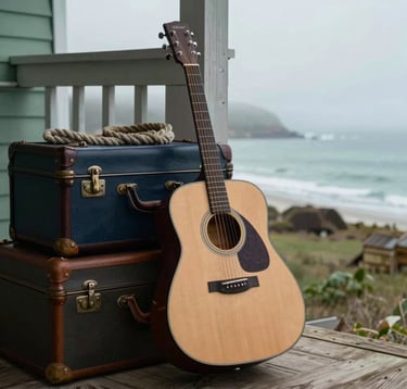 An acoustic guitar leaning against a stack of vintage travel trunks and nautical ropes on a wooden porch overlooking a misty coastal bay. Muted sea green and deep navy color palette, North American Coastal setting.