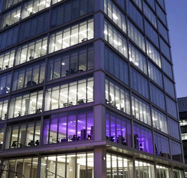 A sharp, high-contrast photograph of a modern tech building at twilight, with glowing white and purple windows reflecting an innovative and sophisticated workspace, North American / Global Professional.