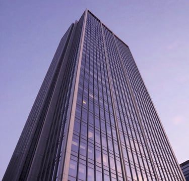 A low-angle shot of a modern corporate skyscraper made of glass and steel, reflecting a clear twilight sky. The architecture is sharp and innovative, colored with soft white and deep violet highlights.