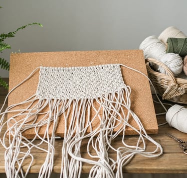 Tejido en macramé para colgar en la pared, rodeada de hilos de artesanía.