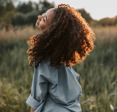curly gurl laughing in the meadow looking up