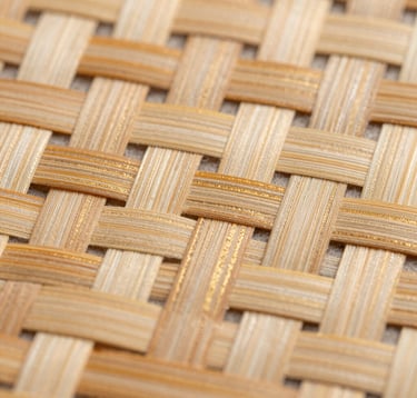 Macro photography of an intricate bamboo weave with a complex geometric pattern. The fibers are a mix of warm beige and soft ivory, with subtle matte gold highlights. Sharp focus on the organic texture and refined craftsmanship.