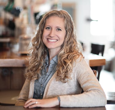 Kara smiling with arm on the table encouraging clients to contact her through the website